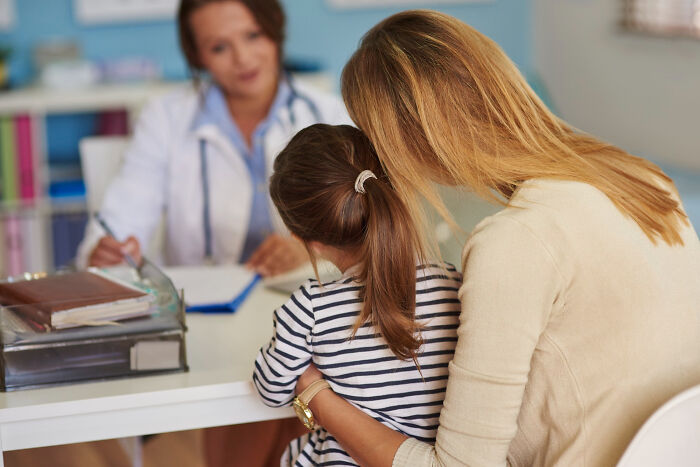 Mother and child consulting doctor about symptoms often brushed off as normal during medical checkup session.