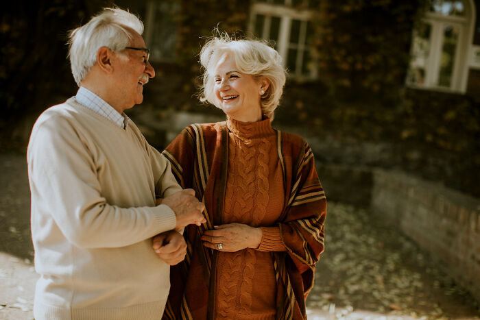 Elderly couple smiling outdoors, illustrating patients brushing off terrifying symptoms as normal, surprising doctors with serious cases.