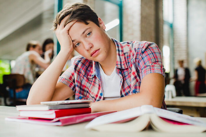 Teenager looking distressed while studying, illustrating patients brushing off terrifying symptoms as normal to doctors' horror.
