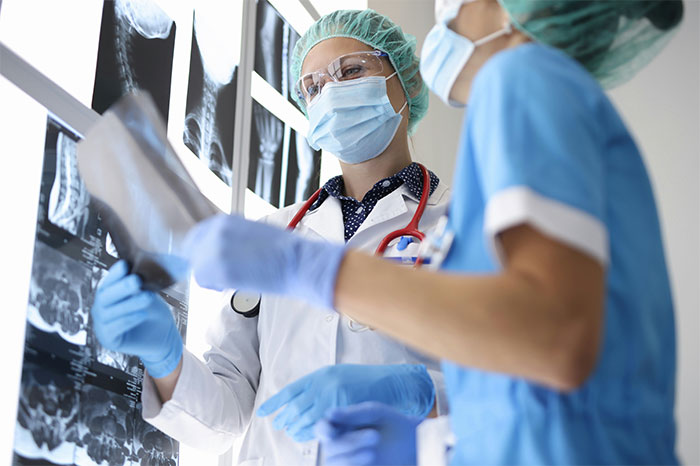 Two surgeons in masks and gloves reviewing X-rays, highlighting bone-chilling stories during surgery awareness cases.