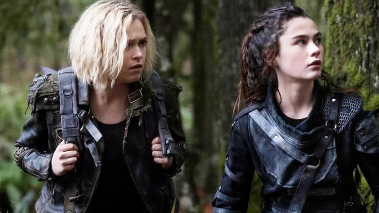 Clarke Griffin (Eliza Taylor) and Madi Griffin (Lola Flannery) stand warily in a forest in The 100
