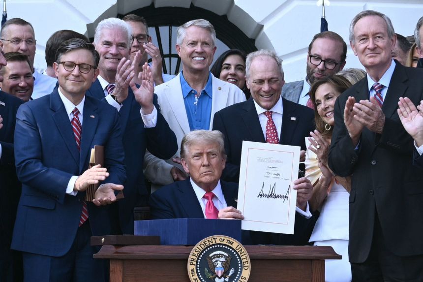 President Donald Trump shows his signature on the