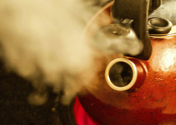 Close-up of steam rising from a red kettle symbolizing unforgettable moments experienced by psychiatric institution workers.