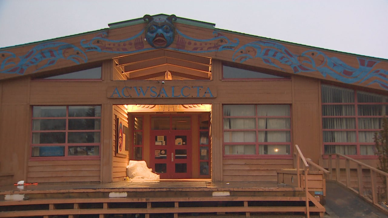 The wooden outdoor facade of Acwsalcta School in Bella Coola, B.C., with Coastal art of fish painted on the eaves