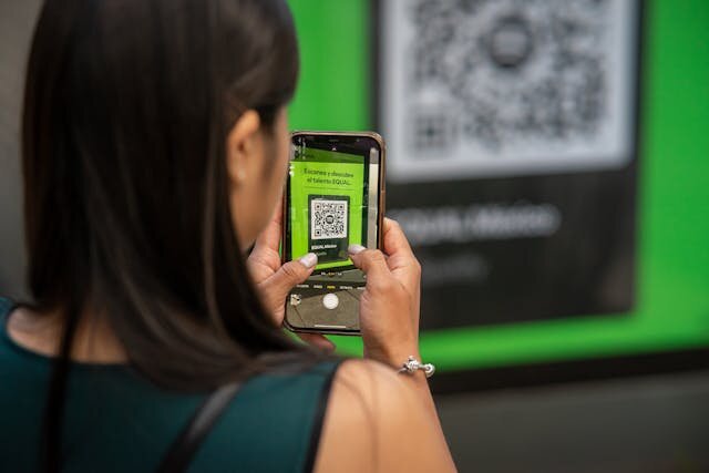 A woman uses her phone to read a QR code with the Camera app.