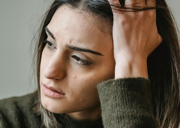 Woman in a green sweater looking contemplative, representing psychiatric institution workers facing unforgettable moments on the job