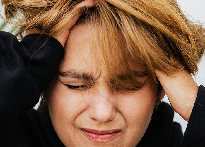 Person holding head in frustration expressing stress, representing unforgettable moments experienced by psychiatric institution workers.