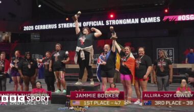 A group of athletes are stood on and around a podium after the world's strongest woman competition. Jammie Booker is on the central podium holding up a trophy.