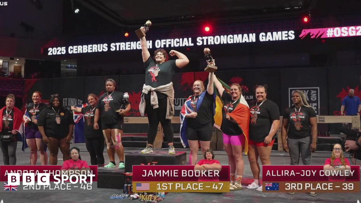 A group of athletes are stood on and around a podium after the world's strongest woman competition. Jammie Booker is on the central podium holding up a trophy.