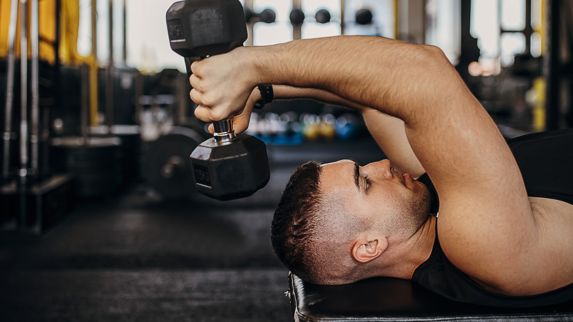 A man performing dumbbell skull crushers