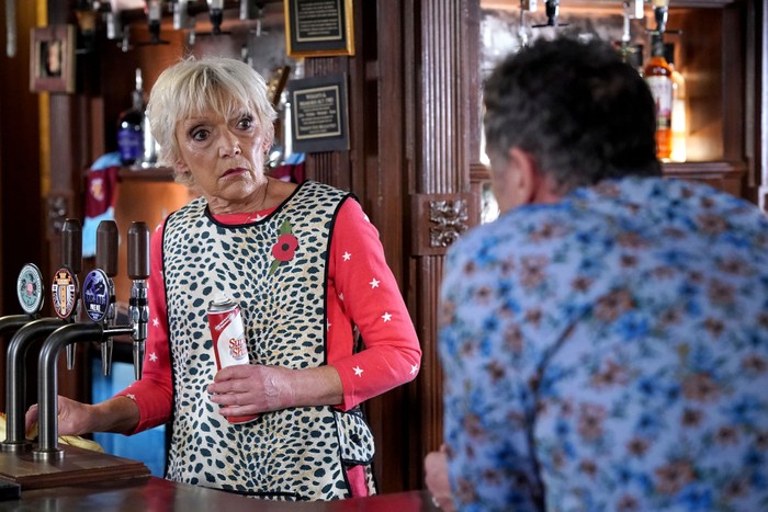 Jean Slater, dressed in an apron and holding cleaning supplies, chats to Alfie Moon in the Queen Victoria in EastEnders