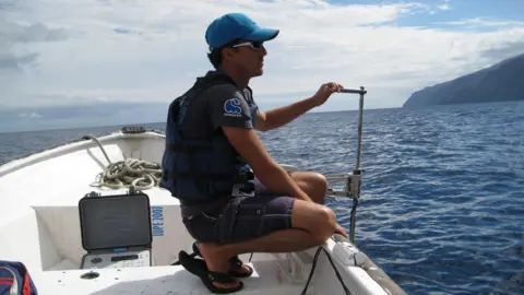 Mauricio Hoyos Mauricio Hoyos crouches on a boat out at sea