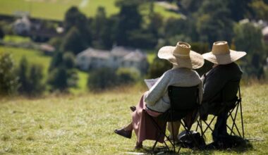 Two elderly people relaxing in the summer sunshine Box Hill near Dorking Surrey England