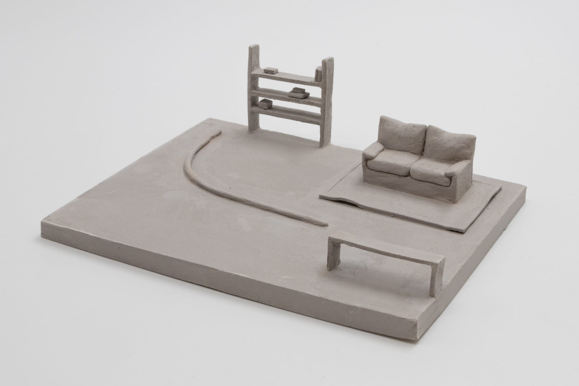 A small ceramic sculpture by Léonore Chastagner of a living room tableau in gray clay