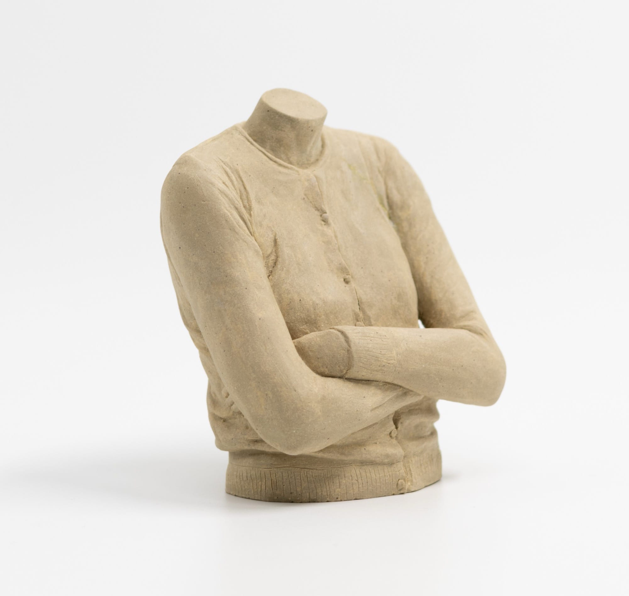 a clay sculpture by Léonore Chastagner of a female torso with a cardigan on and arms folded, with no head