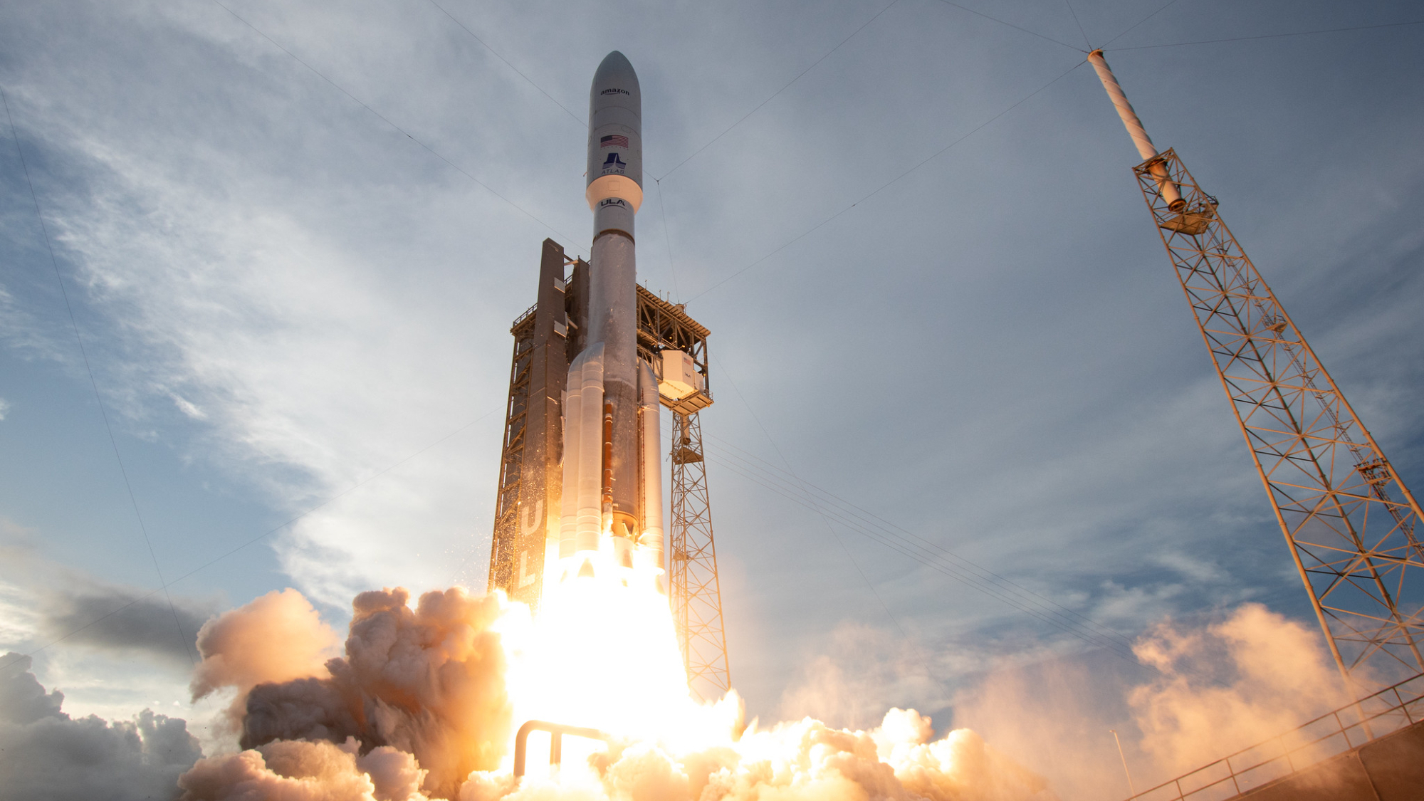 a large white rocket launches into a cloudy blue sky