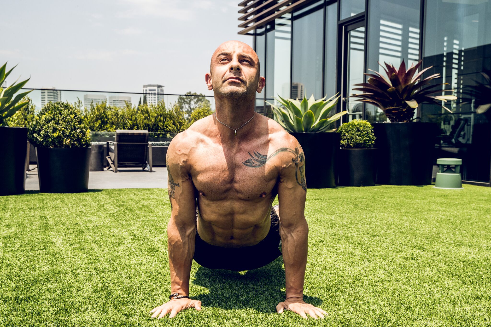 Ed Gemdjian performs a Cobra stretch, holding his torso up with straight arms while his legs lie on the floor behind him.