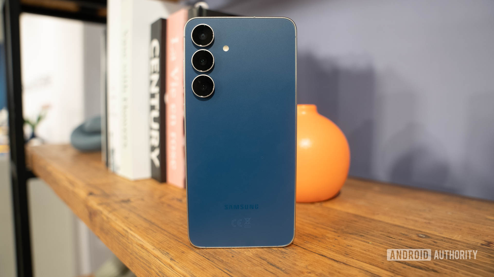 Samsung Galaxy S25 FE in Navy standing on book shelf