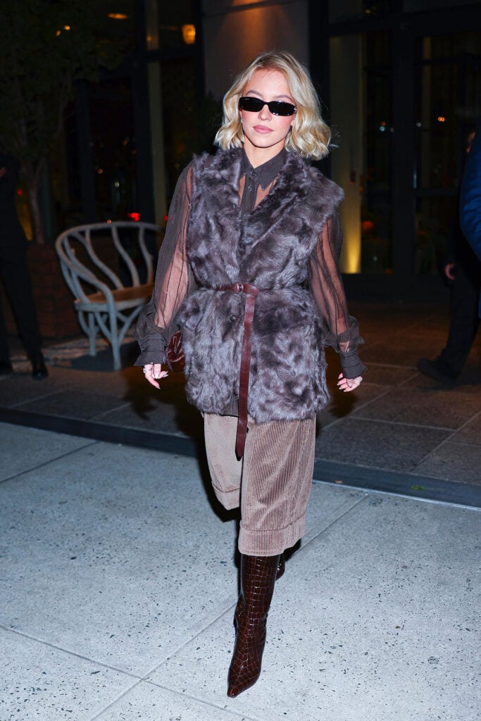 Sydney Sweeney, Brunello Cucinelli Fall 2025, shearling vest, corduroy Bermuda shorts, croc embossed boots, layered textures, New York night style