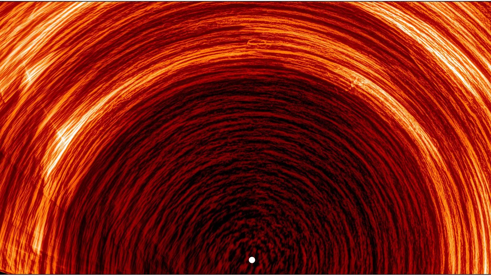 A series of red rings arcing over a white light in the middle of the image