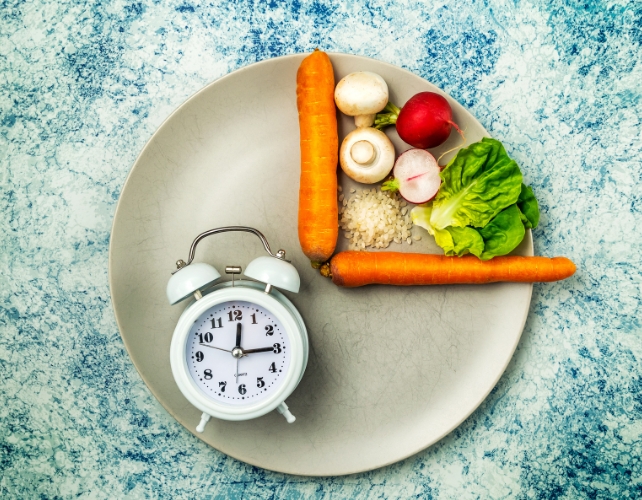 Vegetables on one quarter of a plate, with a clock on the opposite quarter