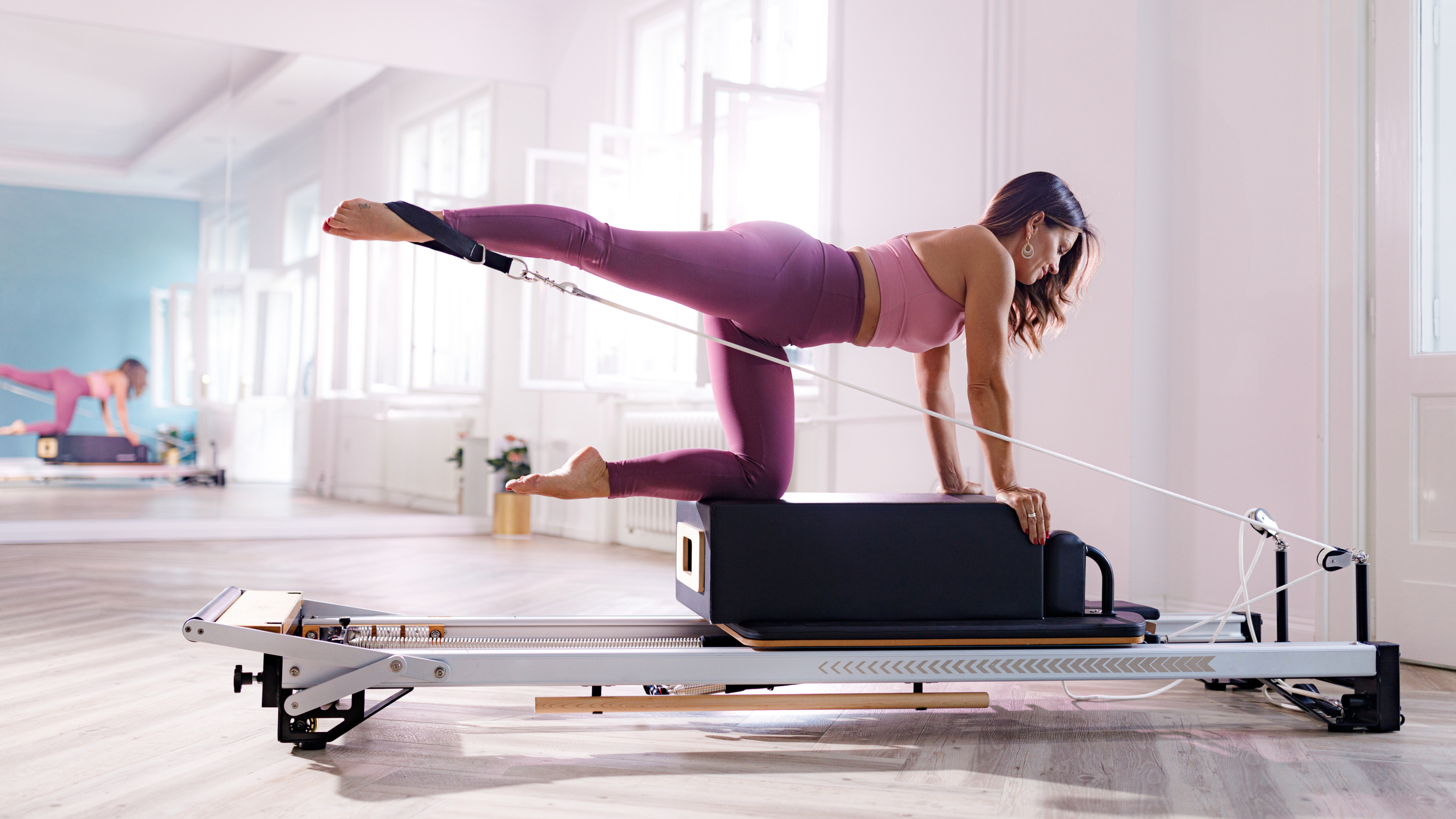 a woman performing the superman stretch on a reformer