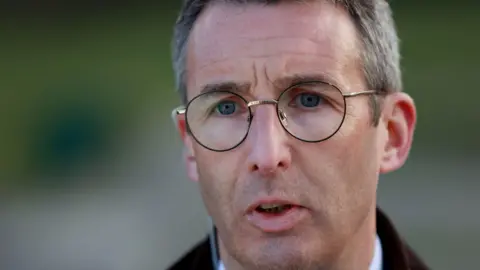 PA Media A close up of Andrew Muir. He has short brown hair which is greying at the sides and is wearing a pair of metal rimmed glasses. 