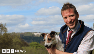 Yorkshire Vet Julian Norton - who is supporting elected mayor David Skaith's mens' mental health campaign - is smiling at the camera, holding Jack Russell dog Emmy and wearing a blue fleece waiscoat.