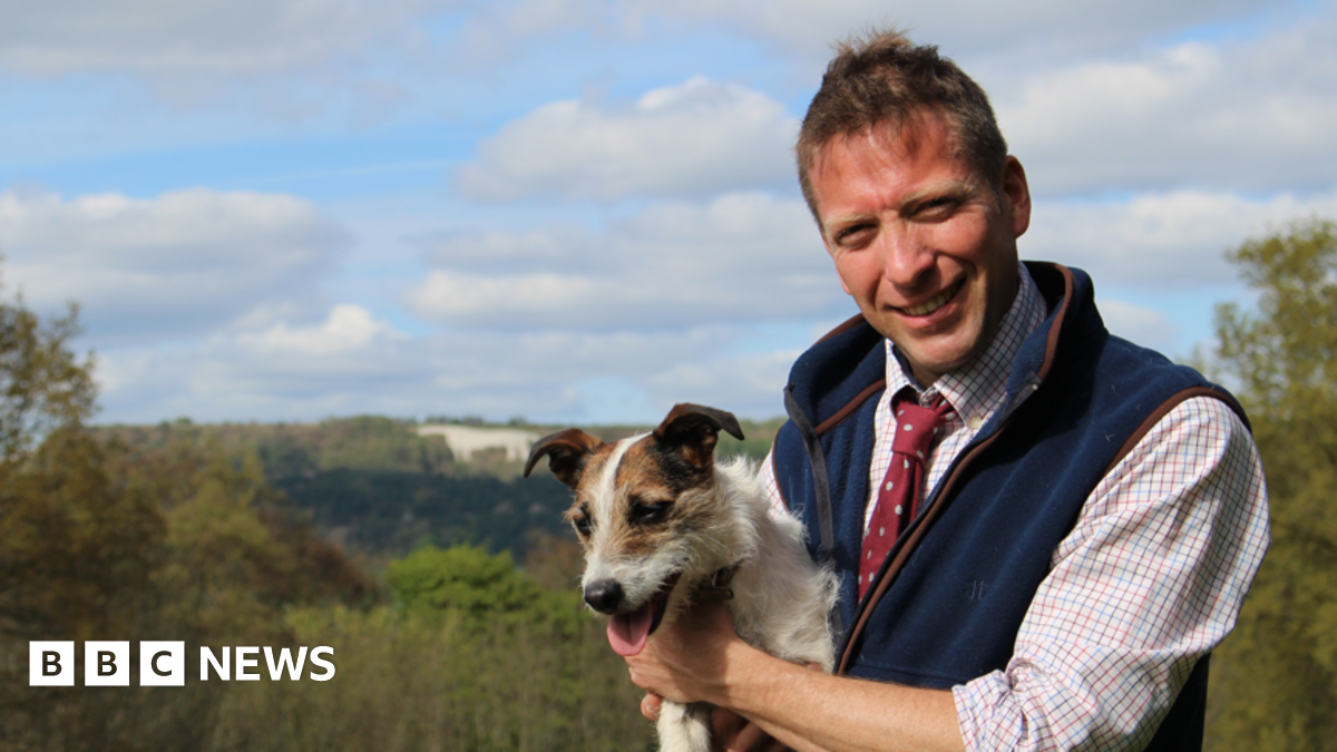 Yorkshire Vet Julian Norton - who is supporting elected mayor David Skaith's mens' mental health campaign - is smiling at the camera, holding Jack Russell dog Emmy and wearing a blue fleece waiscoat.