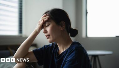 A woman with her eyes closed rests her head in her hand