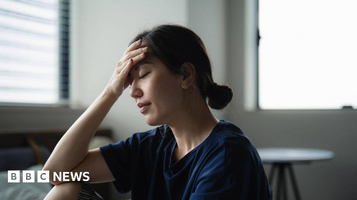A woman with her eyes closed rests her head in her hand