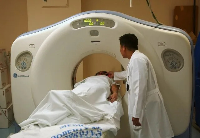 A patient undergoing a CT scan, with a technician present