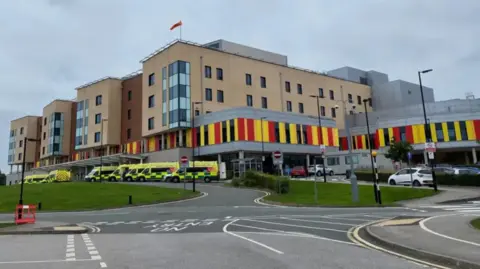 LDRS A multi-storey hospital building, with a number of ambulances parked outside.