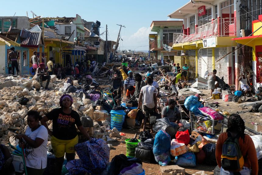 Residents gather amid debris in the aftermath of Hurricane Melissa on a street in Black River, Jamaica, Thursday, Oct. 30, 2025.