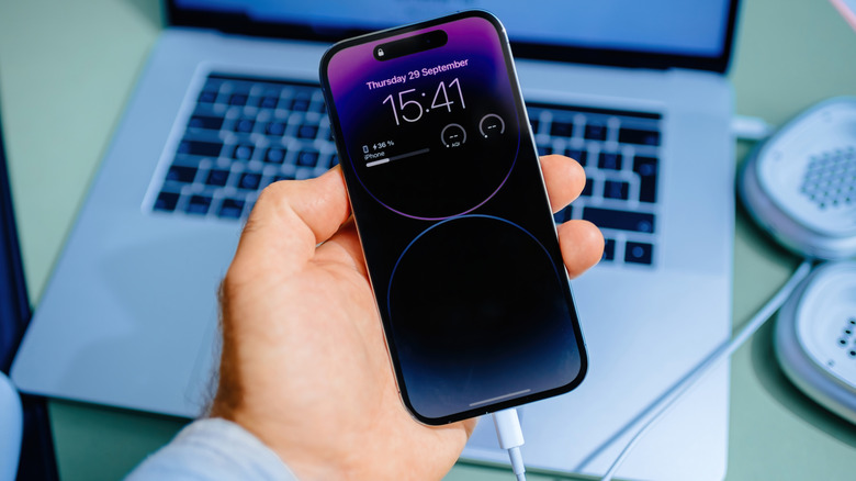 Close up of an iPhone with a MacBook in the background.