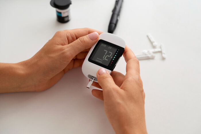 Person checking blood sugar level with a glucose meter while testing diabetes, illustrating Doctor Google vs real doctor concept.