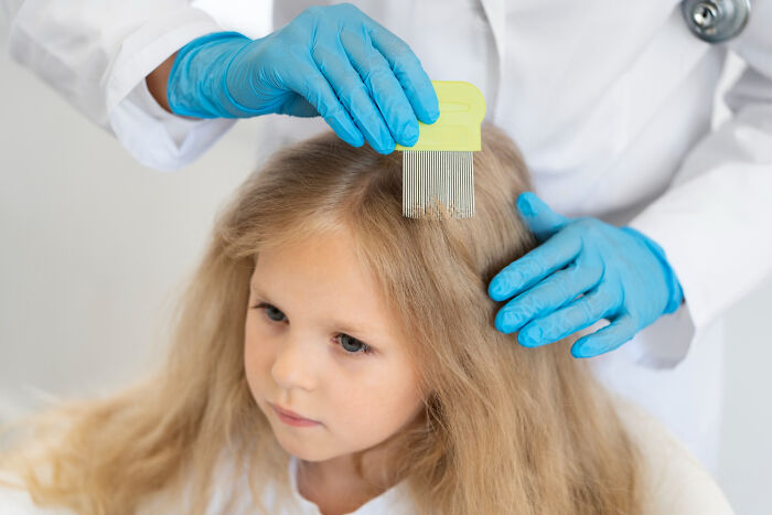 Child getting hair checked by doctor wearing blue gloves, illustrating Dr Google versus real doctor medical checkup debate.