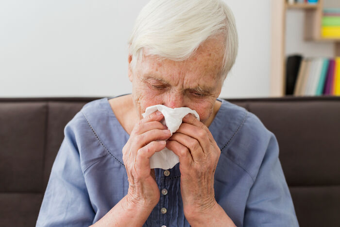 Elderly woman with white hair using tissue to blow nose, illustrating common scenarios where Dr. Google and real doctor advice may differ.
