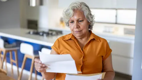 Hispanolistic/Getty Senior woman at home reading a letter she got in the mail 