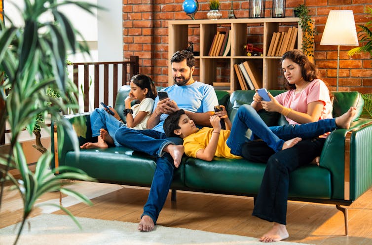 Family on sofa all using devices