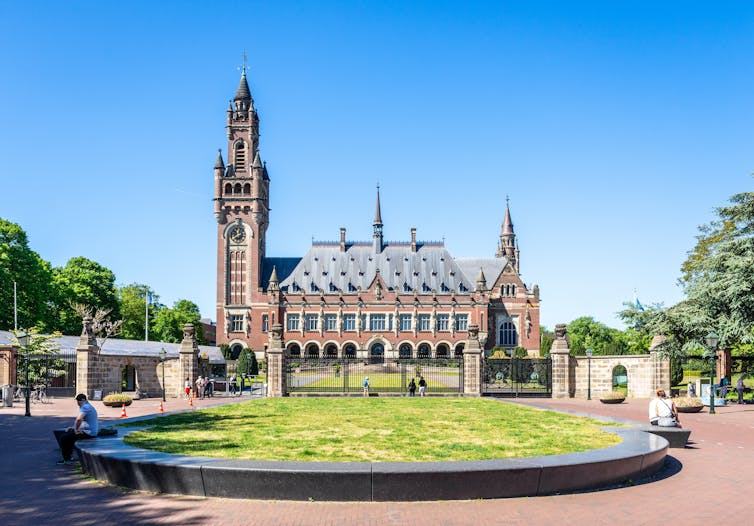 shot of old building where international court of justice is based, green lawn, blue sky
