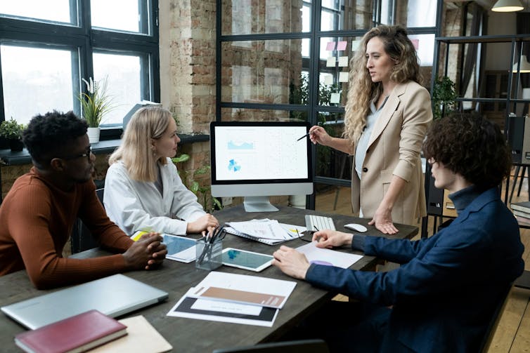 A pregnant office worker presenting to her colleagues during a meeting.