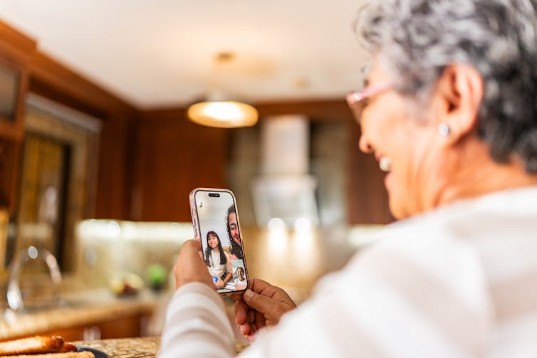 Older woman talking to family on a cell phone video call.