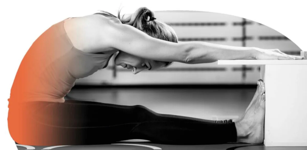 A person sat with their hands and legs stretched out fully, face perpendicular to their knees