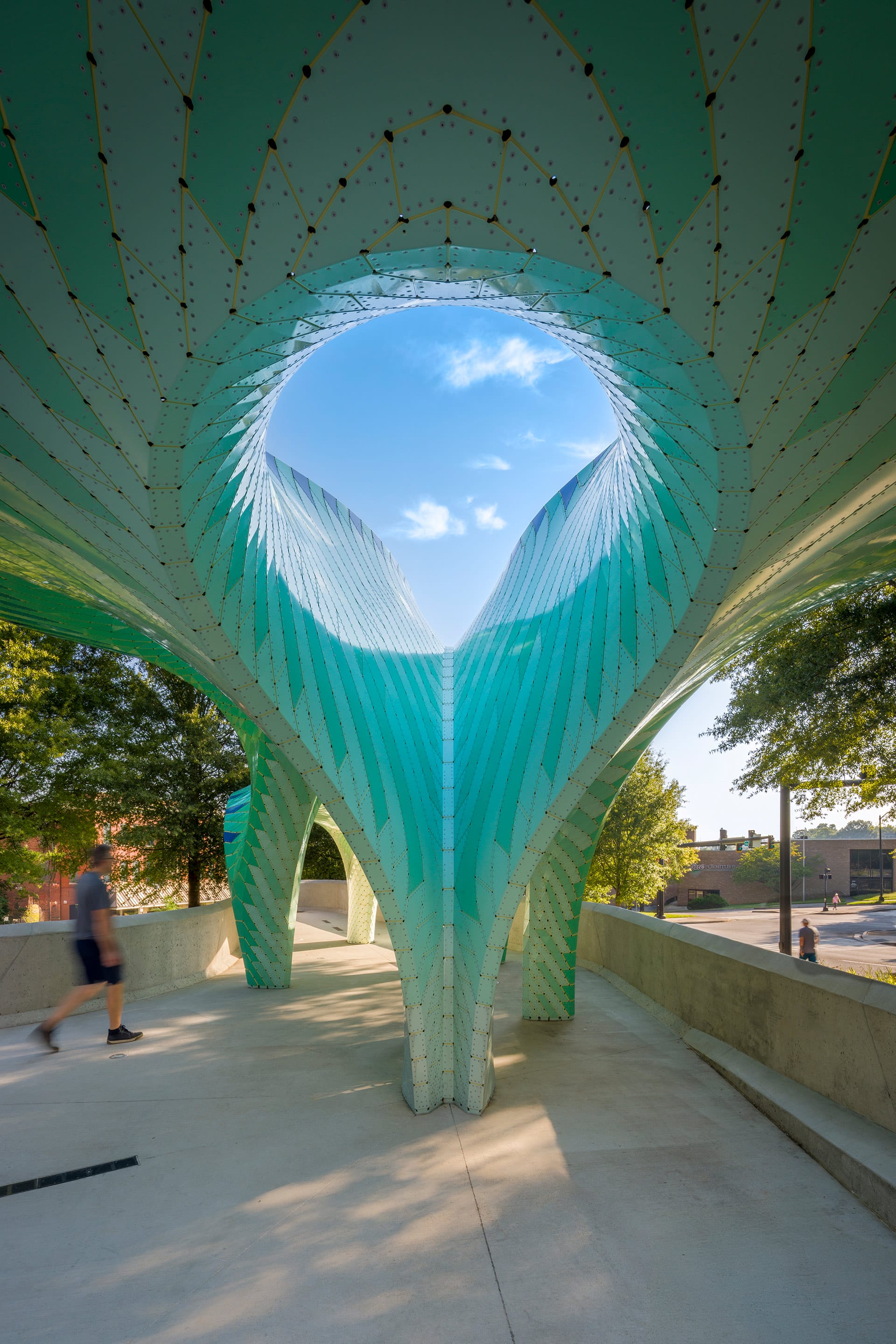 a contemporary, teal-colored pavilion designed by Marc Fornes/THEVERYMANY in a public square in Knoxville, Tennessee