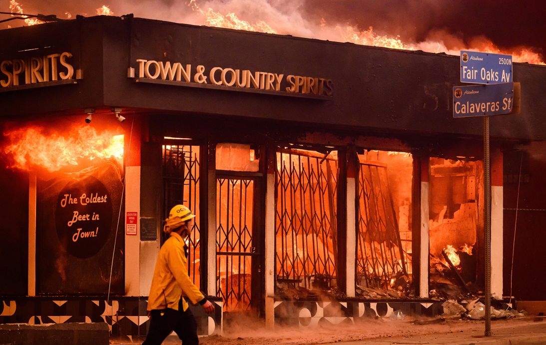 A firefighter walks passed a burning liquor store during the Eaton fire in the Altadena area of Los Angeles County, California on January 8, 2025.