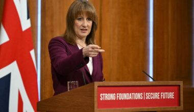 Rachel Reeves gestures while taking questions at a podium with the sign ‘Strong Foundations