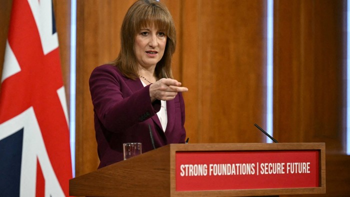 Rachel Reeves gestures while taking questions at a podium with the sign ‘Strong Foundations