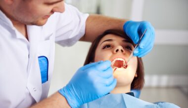 Male doctor in uniform checking up female patient's teeth in dental clinic. Concept of oral examination, toothache and decay treatment.