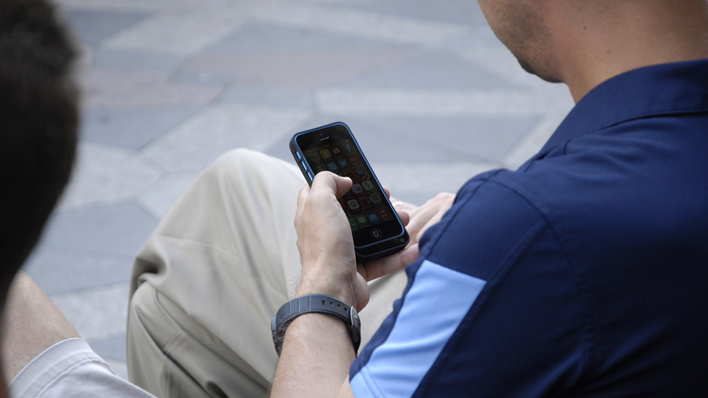 A person using an iPhone on the street.